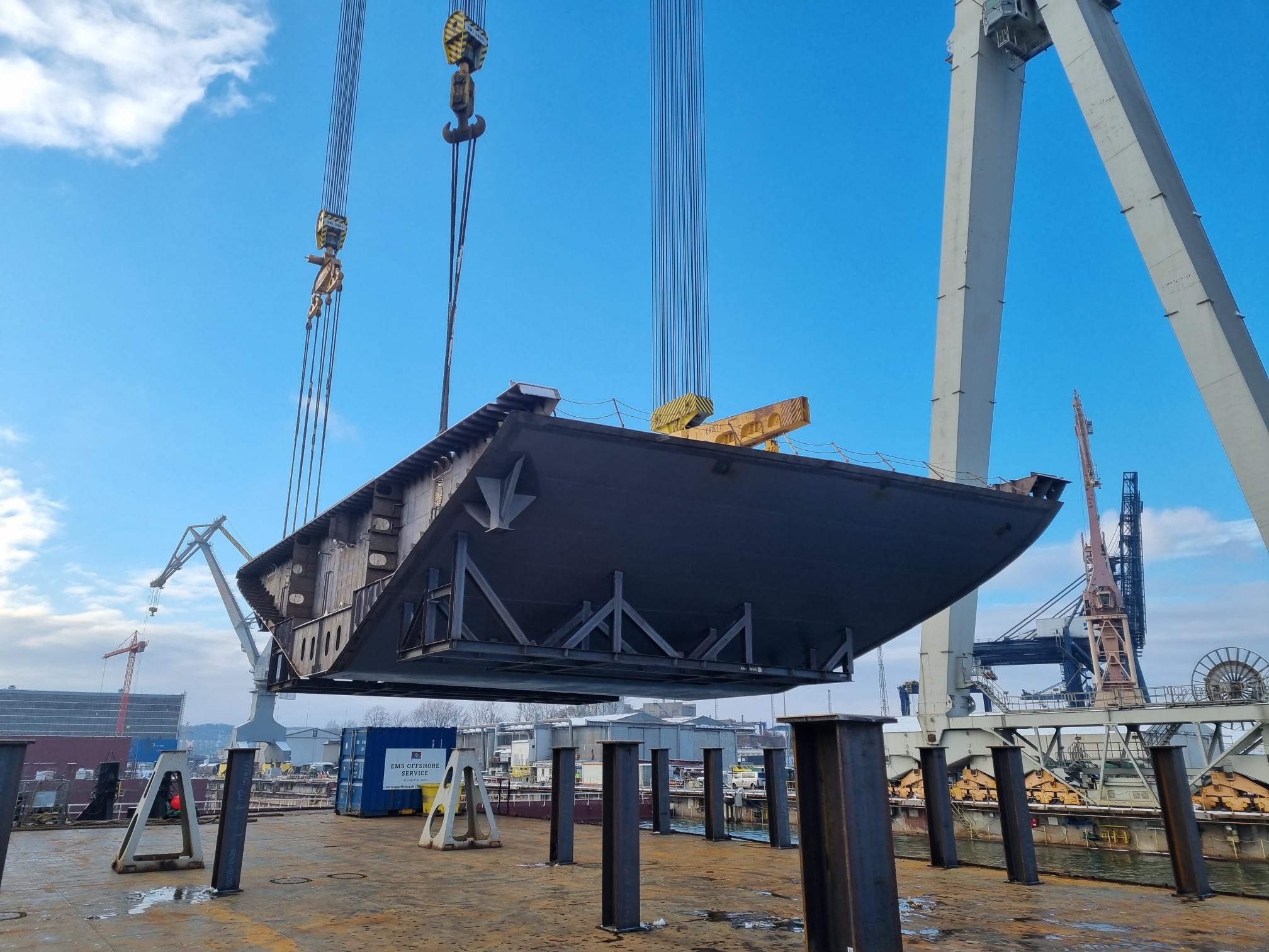 Rumpfsektion eines Kreuzfahrtschiffes wird mithilfe von einem Kran an Bord von einem Ponton gehoben